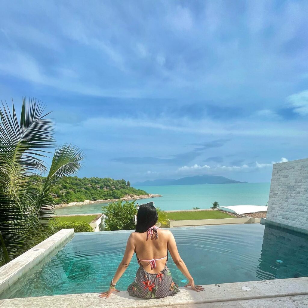 Sharkshe aka Shakshi Shetty relaxing by the pool, wearing a bikini and sitting on a ledge.