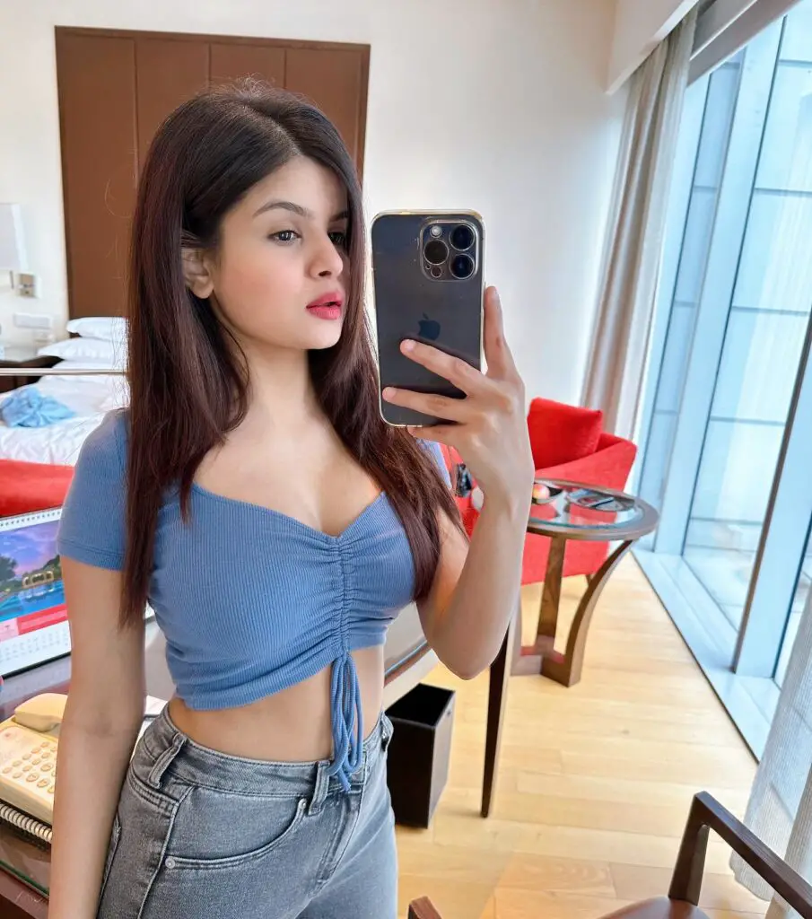  in jeans and a blue top capturing a selfie. Krutika Ojha, the famous YouTube streamer